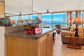 Eine moderne Küche mit Kochinsel, ein Essbereich mit Ausblick und ein Wohnzimmer mit Sofa und Sesseln.
