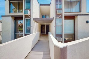 Un immeuble à plusieurs étages doté de balcons, de climatiseurs et d’un couloir central.