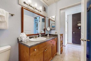 A bathroom with a wooden vanity, a large mirror, a sink, and a towel rack. - *NEW* Room for Eight Near Kamaole III, Pet-Friendly Kihei Condo (Kihei)