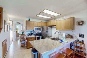 A modern kitchen with wooden cabinets, a central island, a microwave, and a refrigerator. - *NEW* Room for Eight Near Kamaole III, Pet-Friendly Kihei Condo (Kihei)