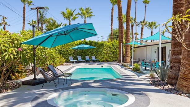 A swimming pool with lounge chairs and umbrellas, surrounded by palm trees and greenery. - The Martini Lounge | Mid-Century with Private Pool (Palm Springs)