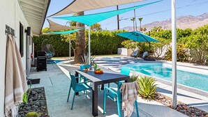 A backyard with a pool, outdoor seating, and a pergola providing shade. - The Martini Lounge | Mid-Century with Private Pool (Palm Springs)