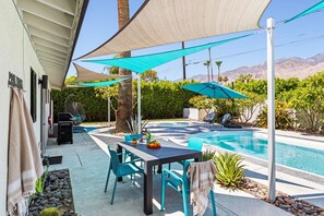 Ein Garten mit Pool, Sitzgelegenheiten im Freien und einem Pergola, das Schatten spendet.