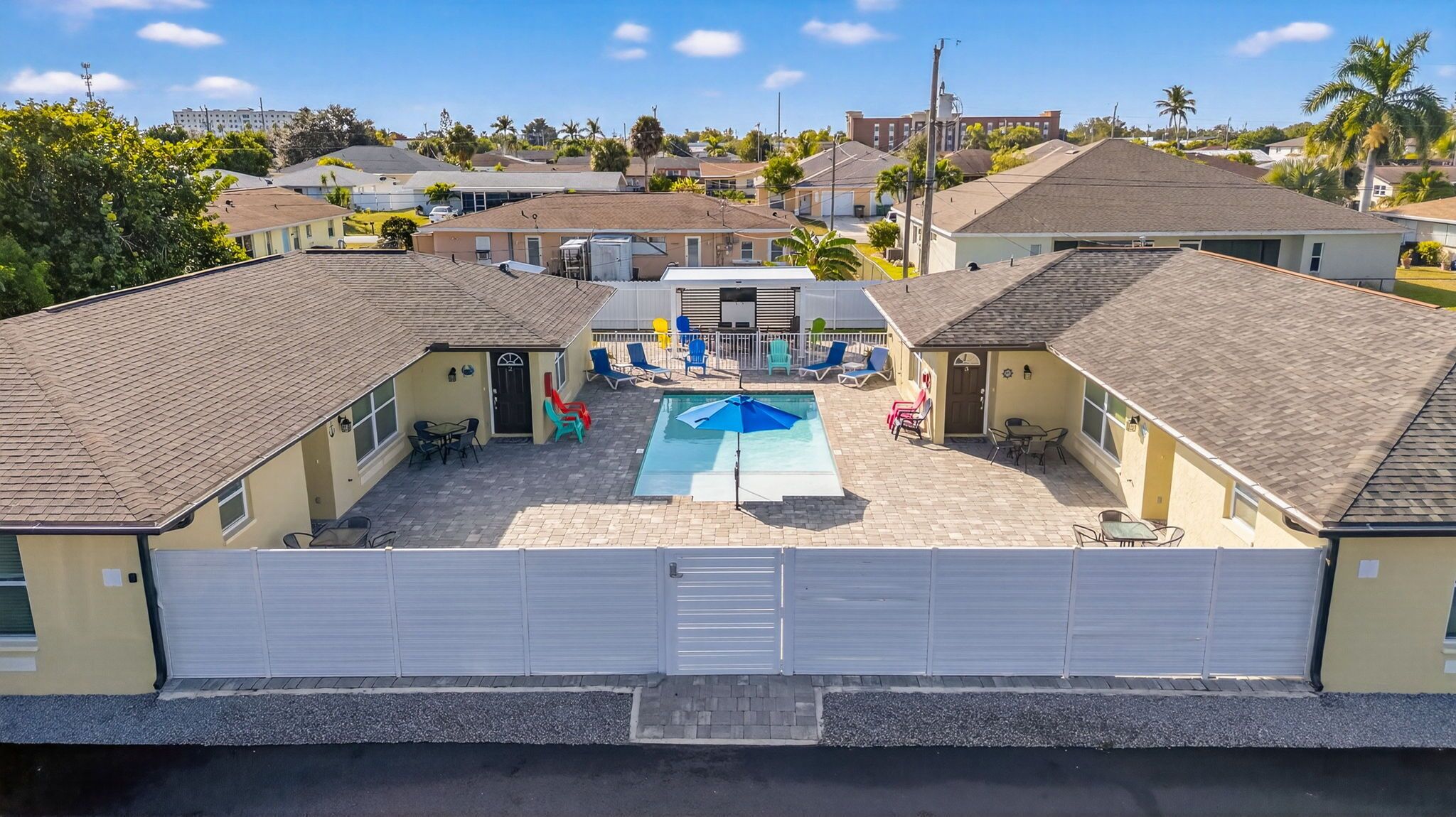 A residential area with a swimming pool, multiple houses, and a clear sky.