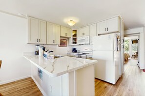 Une cuisine moderne avec des meubles blancs, un îlot en marbre et des appareils électroménagers en acier inoxydable.