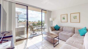 Una habitación de hotel moderna con balcón, un sofá, una mesa de centro y obras de arte en la pared.
