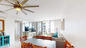 Una sala de estar moderna con comedor, ventilador de techo y vistas al exterior.