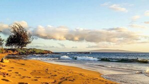 Une plage avec des empreintes de pas, des vagues et un ciel dégagé.