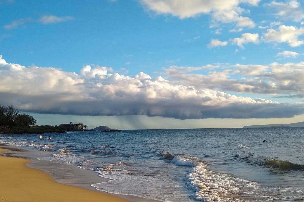 A beach with waves, a clear sky, and a distant building.