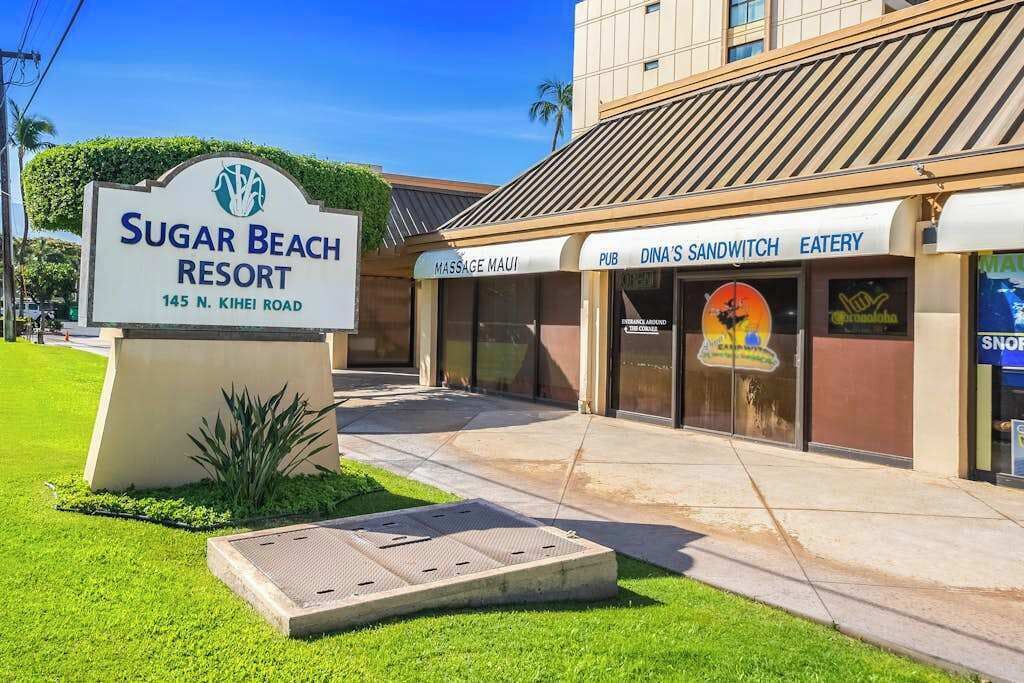 A sign for Sugar Beach Resort with a massage service, a pub, and a sandwich shop.