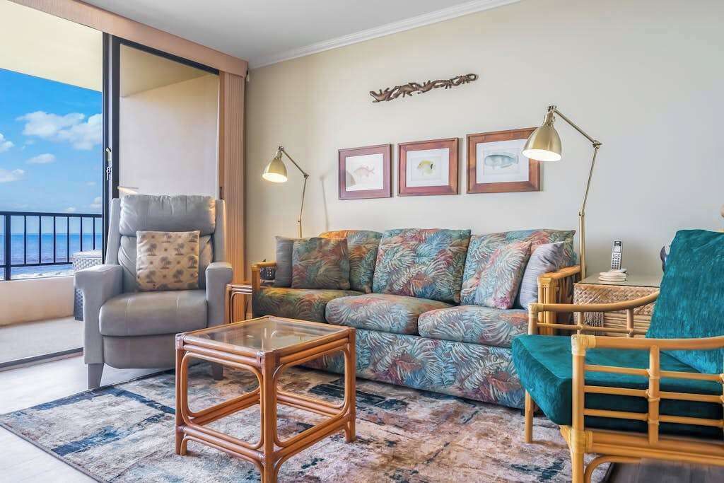 Uma sala de estar com sofá, poltronas, mesa de centro e varanda com vista.