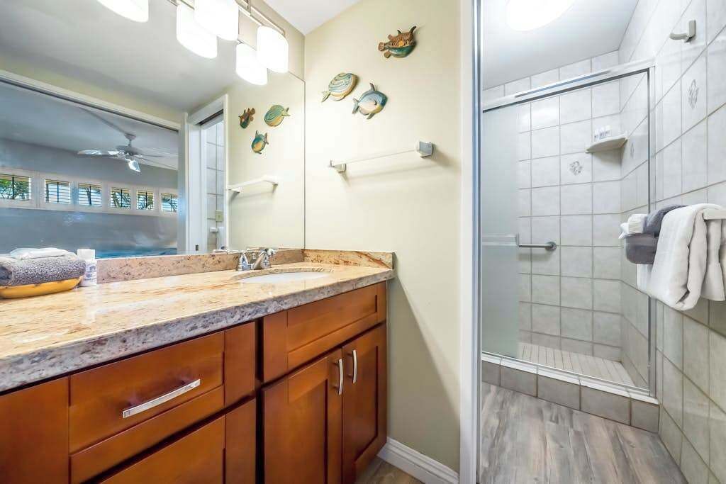 A bathroom with a shower, a sink with a mirror, and decorative fish wall art.