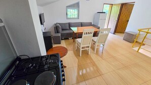 Une cuisine équipée d’une cuisinière, une table à manger avec des chaises, un canapé et une fenêtre.