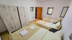 Une chambre avec deux lits, une armoire et une porte donnant sur une autre pièce.