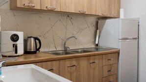 Une cuisine avec des meubles en bois, un évier en acier inoxydable, un réfrigérateur blanc et une machine à café.