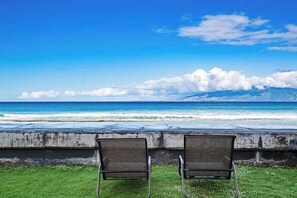 Two chairs facing a beach with ocean and clouds. - New Oceanfront Balcony Views in West Maui (Lahaina)