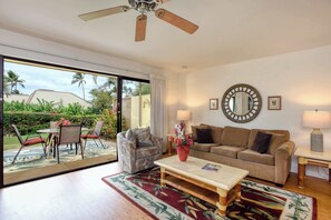 Un salon comprenant un canapé, un fauteuil, une table basse et un ventilateur de plafond.