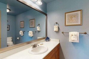 A bathroom with a large mirror, a sink, a toilet, and towel racks. - Relaxing 2BR Kihei Condo Near Beach with Pool and Hot Tub (Kihei)