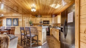 L’intérieur d’une cabane en bois comprend un coin repas, une cuisine et un réfrigérateur.