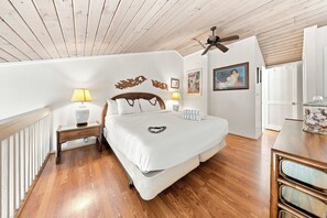 A bedroom with a wooden ceiling, a bed with white bedding, two bedside lamps, and wall art. - Beachside Fun at Mahina Surf Resort Condo - Pool, Laundry, Near Local Activities (Lahaina)