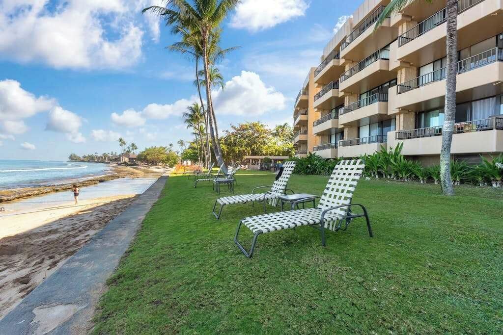 A beachfront hotel with a pool area, palm trees, and a view of the ocean.
