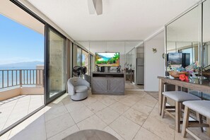 Ein geräumiger Balkon mit Meerblick, eine Sitzecke mit Fernseher und ein Esstisch mit hawaiianischer Dekoration.