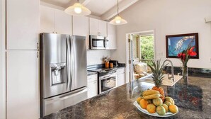 A modern kitchen with stainless steel appliances, a granite countertop, and a fruit bowl. - NEW Fall Sale Ocean-View Wailea Townhouse with Two Shaded Lanais (Wailea)