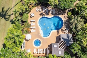 Eine Vogelperspektive eines Resorts mit Swimmingpool, Liegestühlen und Palmen.