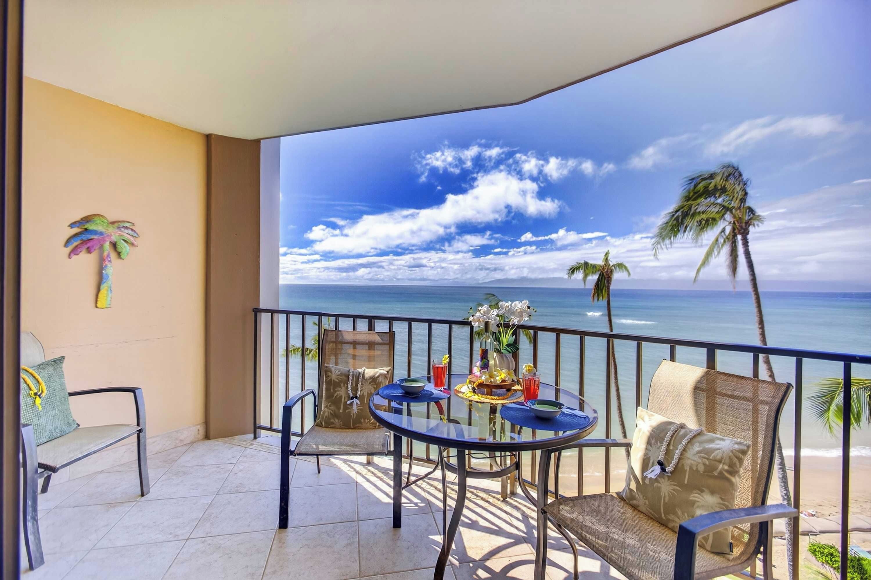 Ein Balkon mit Meerblick, einem Tisch mit Stühlen und dekorativen Kissen.