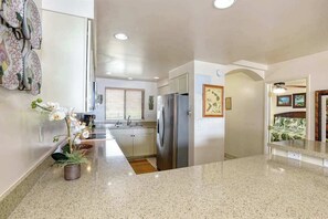 A kitchen with a granite countertop, stainless steel appliances, and a potted orchid. - *New* Fall Deal Oceanfront Ma'alaea Stay, Walk to Beach and Harbor (Wailuku)