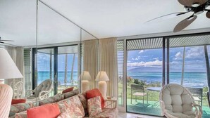 Ein modernes Wohnzimmer mit einem großen Sofa, einem Sessel und Blick auf den Ozean.