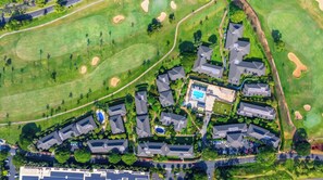 Ett flygbildsbild av ett bostadsområde med hus, en swimmingpool och en golfbana.