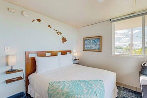 A hotel room with a bed, a window with a view, a painting on the wall, and a map of Hawaii. - Kihei Studio Retreat at Keawakapu Beach- Kitchen, Laundry, Ocean/Mountain Views (Kihei)