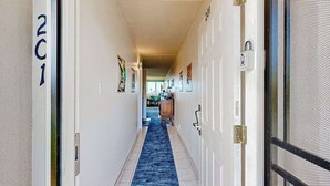 Un couloir avec un tapis bleu, des murs blancs et des portes numérotées 201 et 202.