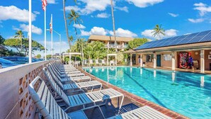 A swimming pool with lounge chairs, palm trees, and a building with solar panels. - *New* Fall Special Garden Lanai Retreat Near Kamaole II (Kihei)