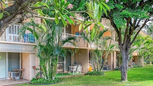 Un hotel con varios balcones, mobiliario exterior y abundante vegetación.