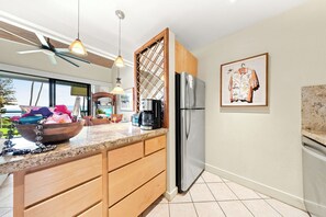 A modern kitchen with a large island, stainless steel appliances, and a view to the outside. - Mahina Surf Oceanfront Resort Condo-Pool, BBQ, Kitchen, Lanai, Sea Turtle Beach (Lahaina)