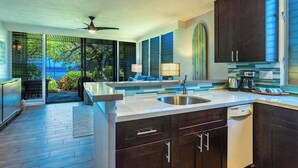Una cocina moderna con una isla grande, muebles oscuros y vistas al exterior.