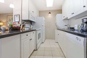A compact kitchen with white cabinetry, a microwave, a stove, and a sink. - New Fall Deal Maalaea Bay Sunsets from a Private Ocean-View Lanai (Wailuku)
