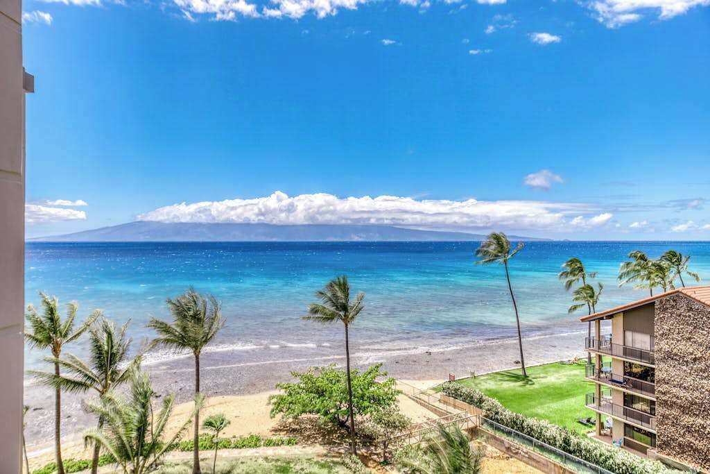 A beachfront hotel with a view of the ocean and a mountain in the distance.