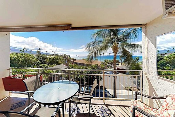 A balcony with a table and chairs, a view of the sea, and palm trees. - *New* Fall Special Kihei Ocean Views Steps from Kalama Beach and The Cove (Kihei)