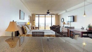 Una camera d'albergo con un letto, una scrivania, una sedia, una televisione e un balcone.