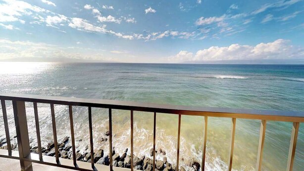 Vista della costa con ringhiera, cielo sereno e onde oceaniche.