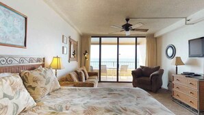 Una camera d'albergo con un letto, un divano, una sedia, una TV e un balcone con vista.