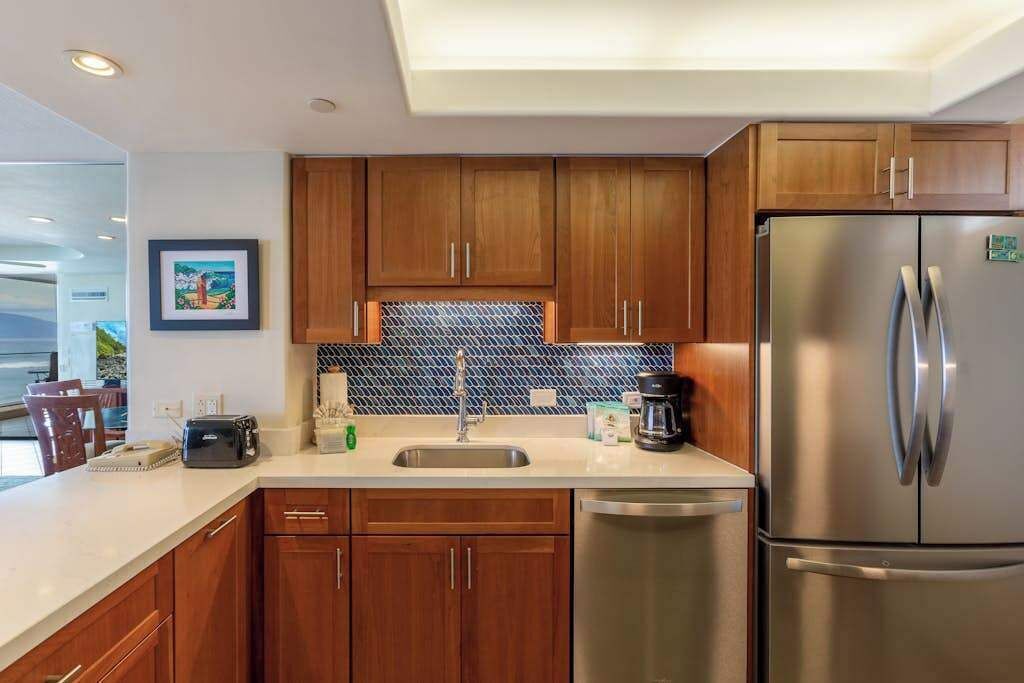 A modern kitchen with wooden cabinets, a stainless steel refrigerator, and a tiled backsplash.