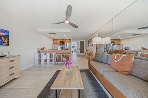 A modern living room with a sofa, coffee table, and a view of the kitchen. - *NEW* Fall $pecial Ground-Floor Beachfront Lahaina Condo with Pool (Lahaina)