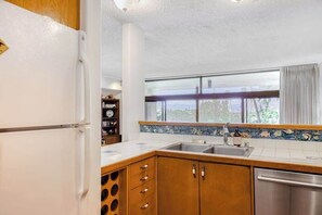 Eine Küche mit Kühlschrank, Holzschränken, Spüle und einem Fenster mit Blick.