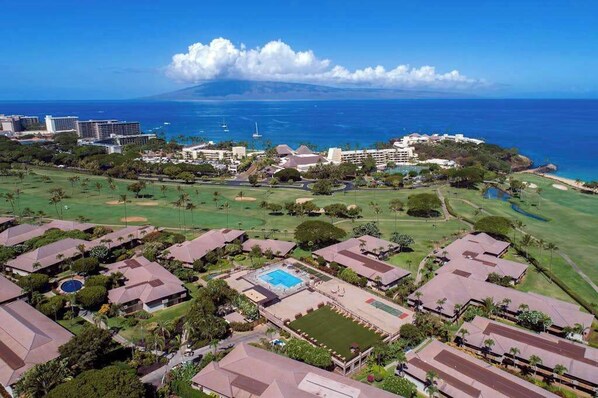 A resort with multiple buildings, a golf course, and a view of the ocean.