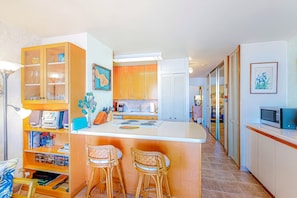 A compact kitchen with a central island, wooden cabinets, and a microwave. - New 70 Feet from Ma'alaea Bay, Pool and Hot Tub (Wailuku)