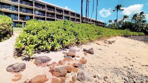 A multi-story hotel with balconies, a sandy beach area, and tropical vegetation. - New 70 Feet from Ma'alaea Bay, Pool and Hot Tub (Wailuku)